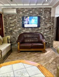 skórzaną kanapę w salonie z telewizorem na kamiennej ścianie w obiekcie Nador cornich Apartement w mieście Nador