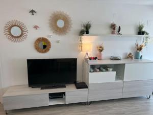 uma sala de estar com uma televisão de ecrã plano e espelhos em Apartamento cerca de la playa em Denia