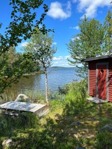 un pequeño edificio rojo junto a un cuerpo de agua en Camp Caroli 2.0, en Jukkasjärvi