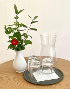 une table avec un vase, deux verres et une fleur dans l'établissement Gullringens Värdshus & hotell, à Gullringen