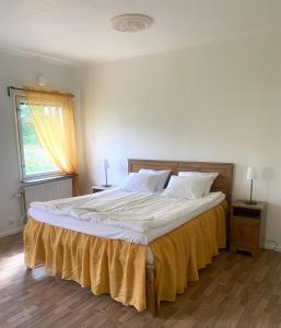 una camera da letto con un grande letto con lenzuola bianche e una finestra di Gullringens Värdshus & hotell a Gullringen