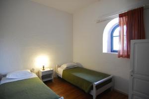 two beds in a small room with a window at Karavostassi - The Stonehouse in Agios Nikolaos