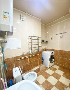 a bathroom with a toilet and a washing machine at Уютные апартаменты 5 микрорайон in Aktau