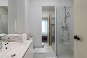 uma casa de banho branca com um chuveiro e um lavatório. em Hobbit Hotel Mechelen em Mechelen