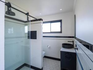 a bathroom with a glass shower and a toilet at Mermaid Apartments in Merimbula