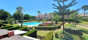 伊斯蘭蒂拉的住宿－Adosado en Islantilla，享有带游泳池和树木的别墅的正面景色