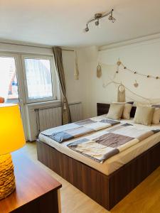 Cama grande en habitación con lámpara amarilla en Klebi’s apartmanház, en Balatonföldvár