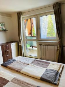 1 dormitorio con 1 cama y 2 ventanas en Klebi’s apartmanház, en Balatonföldvár