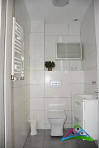 a white bathroom with a toilet and a sink at Uroczy Zakątek 1 in Grzybowo