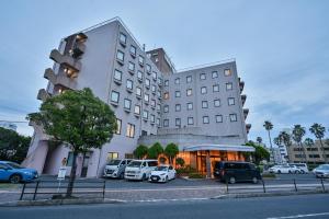 a large white building with cars parked in a parking lot at Kagoshima Daiichi Hotel Kamoike in Kagoshima