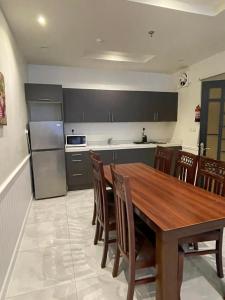 a kitchen with a wooden table and a refrigerator at منتجع جزيرة الروز بالهدا in Al Qubsah