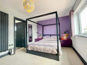 a bedroom with a canopy bed with purple walls at Farne Island rooms in Seahouses