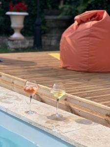 dos copas de vino sentadas en el borde de una piscina en L'ESCALE Chambres et table d'hôtes, en Verdun-sur-le-Doubs