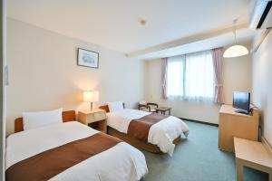 a hotel room with two beds and a television at Kagoshima Daiichi Hotel Kamoike in Kagoshima