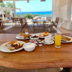 a table topped with plates of breakfast foods and orange juice at Elafonisos Mare in Elafonisos