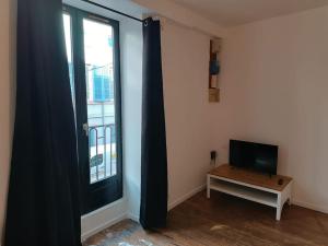 a room with a television and a table and a window at La garçonnière de Gégé in Tournus
