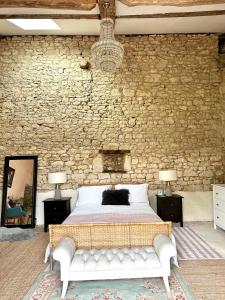a bedroom with a bed and a stone wall at Figtrees in Margueron