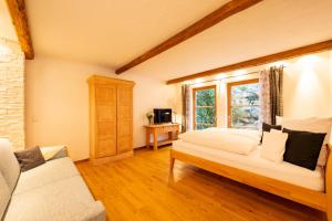 ein Schlafzimmer mit einem Bett, einem Sofa und einem Fenster in der Unterkunft Ferienhaus Weinklause am Plattenbichl in Oberstdorf