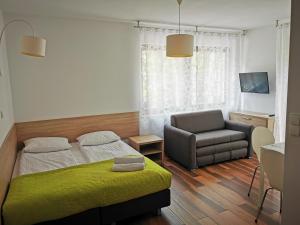 a bedroom with a bed and a couch and a chair at Villa Veell - tylko 4 minuty od pięknej szerokiej plaży in Pobierowo