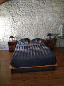a bedroom with a bed and a stone wall at gîte 4 chambres à Cognac in Cognac