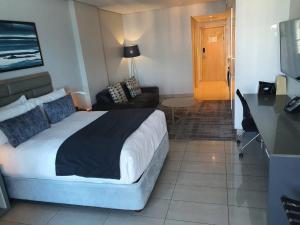 ein Hotelzimmer mit einem Bett, einem Schreibtisch und einem Zimmer in der Unterkunft The Pearls Luxury Studio Apartments - Full Sea View in Durban