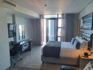 een hotelkamer met een bed, een bureau en een raam bij The Pearls Luxury Studio Apartments - Full Sea View in Durban