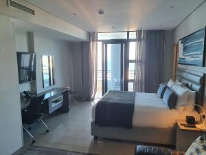 Una habitación de hotel con una cama, un escritorio y una ventana. en Pearls Full Sea View Luxury Studio - Self Catering, en Durban