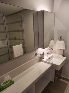 ein Bad mit einem Waschbecken und einem Spiegel in der Unterkunft The Pearls Luxury Studio Apartments - Full Sea View in Durban