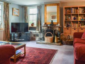a living room with a fireplace and a tv at The Cottage in Blakeney