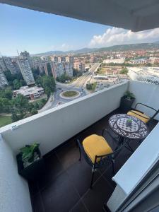 a balcony with a table and chairs and a city at Apartman Bonaca in Niš
