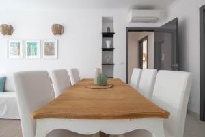 a dining room with a wooden table and white chairs at Elios by PortofinoHomes in Portofino