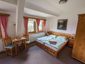 a bedroom with a bed and a table and chairs at Pension Krakonoš in Špindlerův Mlýn