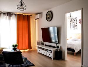 uma sala de estar com uma cama e uma televisão de ecrã plano em Appartement nouveaux quartier Bologne à deux pas de Mosson, WiFi, climatisation et parking gratuit em Montpellier