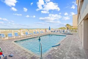 a pool with chairs and a person in the water at Oceanside 302 in Clearwater Beach