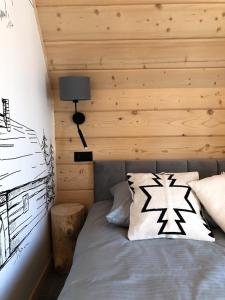 a bedroom with a bed with a wooden wall at RELAS - przytulny domek z dwoma sypialniami i antresolą in Murzasichle