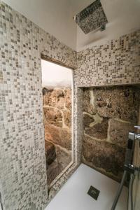 y baño con ducha con ventana y pared de piedra. en La Piazzetta Affittacamere Ristorante, en Anagni