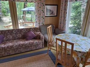 uma sala de estar com um sofá e uma mesa em Lakeside Hilda, rantamökki 