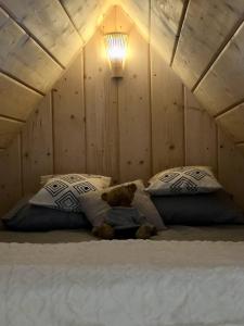 a teddy bear laying on a bed with two pillows at RELAS - przytulny domek z dwoma sypialniami i antresolą oraz JACUZZI in Murzasichle