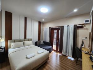a bedroom with a bed and a couch and a window at LeMae Residence เลอเม เรสซิเดนซ์ อำเภอเขาย้อย เพชรบุรี in Ban Huai Krathaek