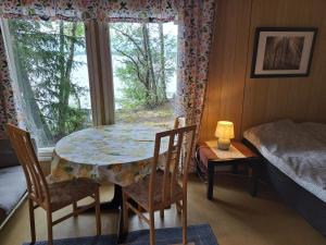 a table and chairs in a room with a window at Lakeside Hilda, rantamökki 