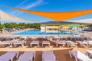 a resort with a pool and white lounge chairs at Apartmány Catalina in Nesvady