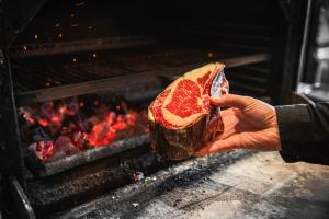 a person holding a piece of meat in an oven at Paping Hotel & Spa - Rest Vonck by Flow in Ommen