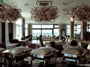 a restaurant with tables and chairs and chandeliers at Baltivia Sea Resort in Mielno