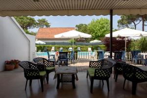 eine Terrasse mit Stühlen, Tischen und Sonnenschirmen in der Unterkunft Hotel Rosa Dei Venti in Lignano Sabbiadoro