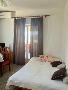 - une chambre avec un grand lit blanc et une chaise dans l'établissement Apartmani Luka, à Korčula