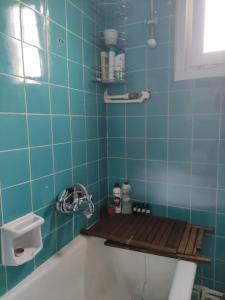 a blue tiled bathroom with a bath tub with a wooden seat at Our flat is located in Beşiktaş Square. in Istanbul