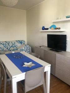 sala de estar con mesa blanca y TV en LE COLONIE Apartments, en Porto Cesareo