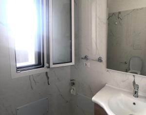 Baño blanco con lavabo y espejo en LE COLONIE Apartments, en Porto Cesareo