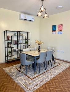 a dining room with a table and chairs on a rug at Deluxe Apartment in Muscat