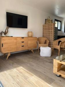 ein Wohnzimmer mit einem TV und einer Holzkommode in der Unterkunft Maison avec ses 2 terrasses et sa piscine in Eyragues